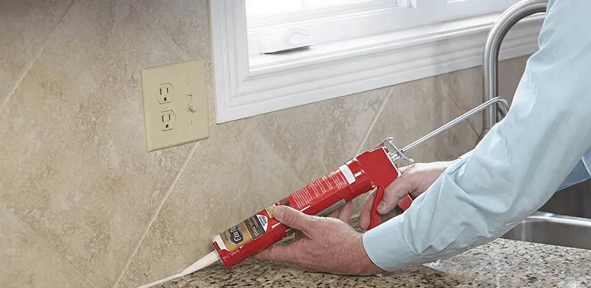 Handyman applying caulk along a kitchen backsplash and countertop seam in New Haven, CT